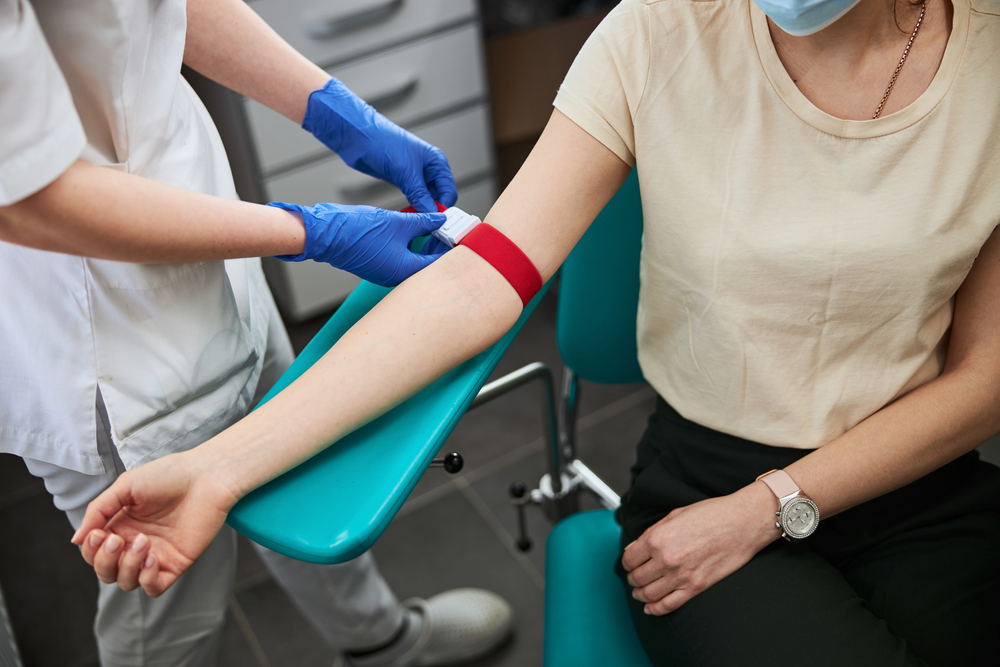 phlebotomist preparing a woman's arm to draw blood